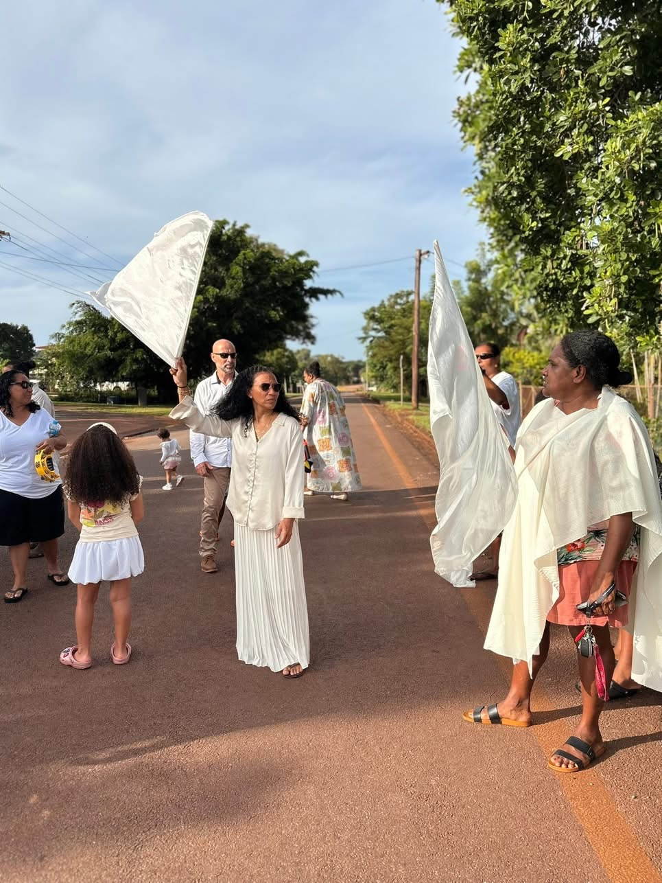 Participants carrying white flags during the Jesus Walk through a street in Bamaga