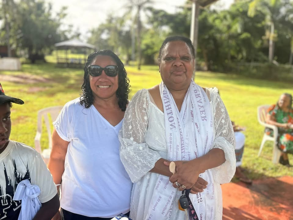 Two women standing outdoors with children nearby